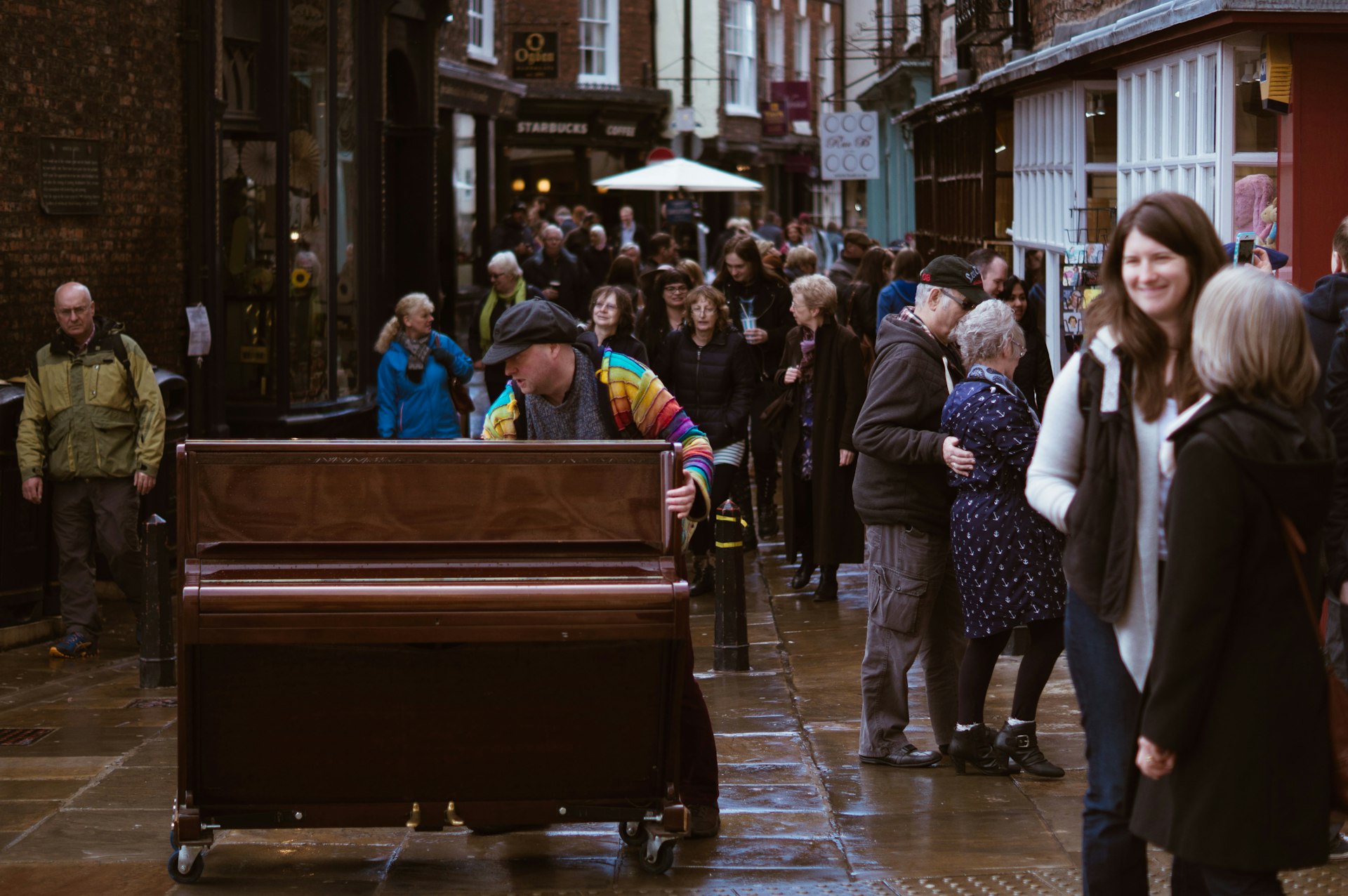 a group of people walking down a street next to a piano